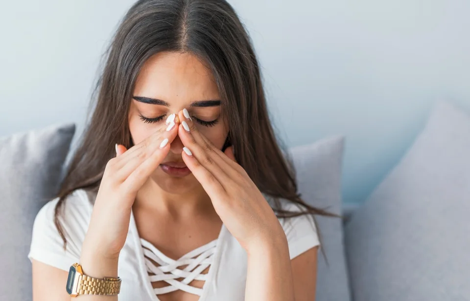 Sinus ache causing very paintful headache. Unhealthy woman in pain. Sharp strong sore. Sinus pain, sinus pressure, sinusitis. Sad woman holding her nose and head because sinus pain