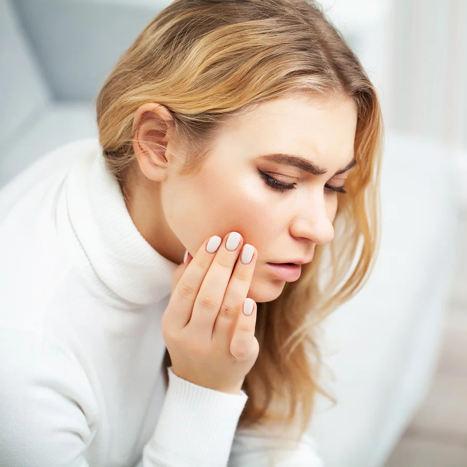 Pain. The problem of teeth. A woman feels pain in her tooth. A picture of a beautiful, sad girl suffering from severe pain in her teeth. An attractive woman feels painful toothache